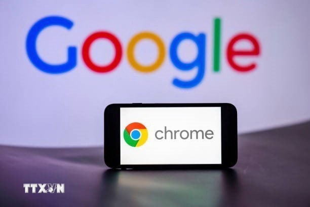 Biểu tượng Chrome trên màn hình điện thoại và biểu tượng Google (phía sau). (Ảnh: Getty Images/TTXVN)